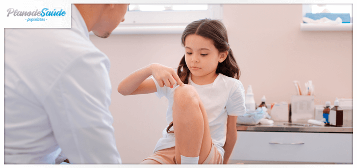 Menina apontando para o seu joelho e falando com médico - dor do crescimento