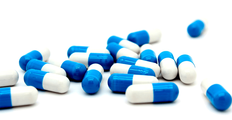 pílulas azul e branca espalhadas em uma mesa - coronavírus