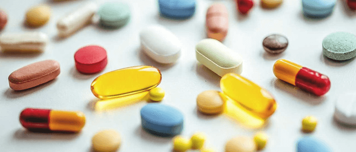 Diversas pílulas e comprimidos espalhados em uma mesa - medicamentos
