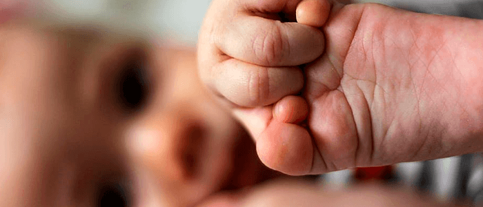Bebê segurando o pé - parto humanizado