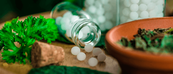 Cápsulas de homeopatia ao lado de ervas